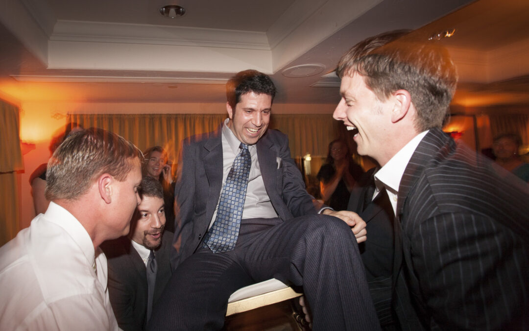 groom at wedding is lifted on chair