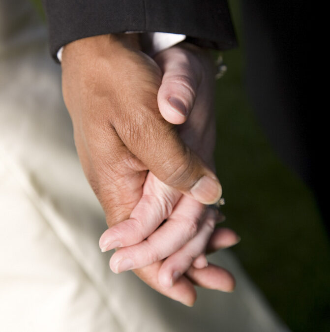 interracial couple holding hands at their wedding
