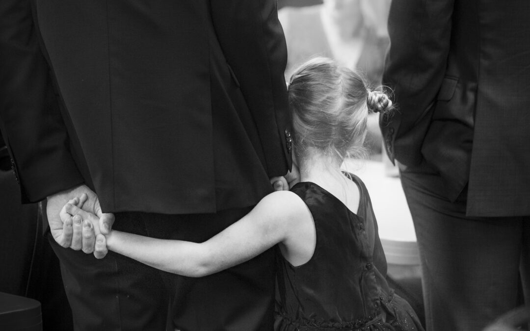 little girl hugs groomsman before wedding