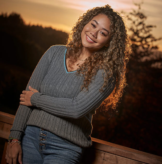 smiling young woman against sunset background