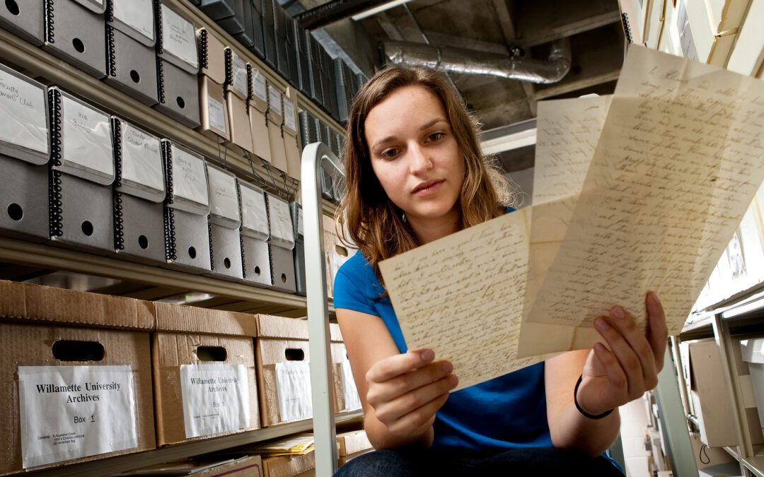 young woman reads handwritten notes in archive