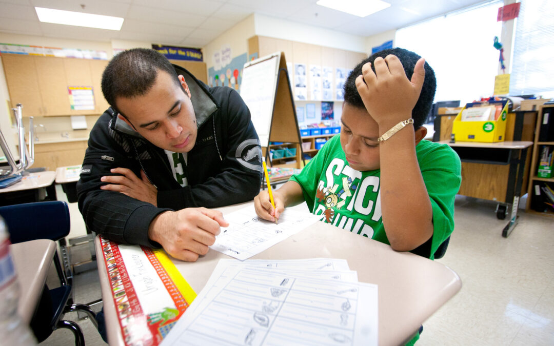 young latino man helps child with schoolwork