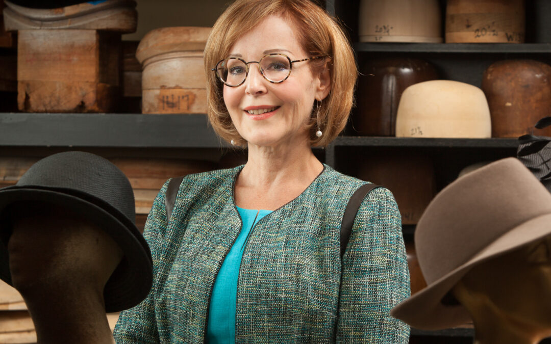 professionally dressed woman surrounded by hats