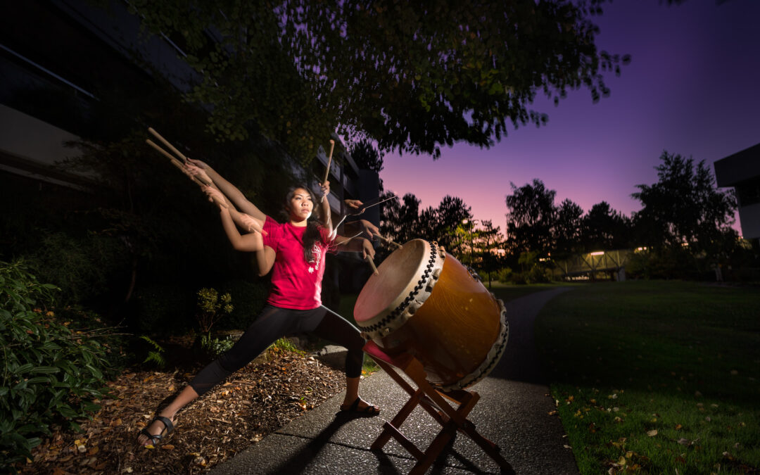 asian woman playing drum in front of sunset