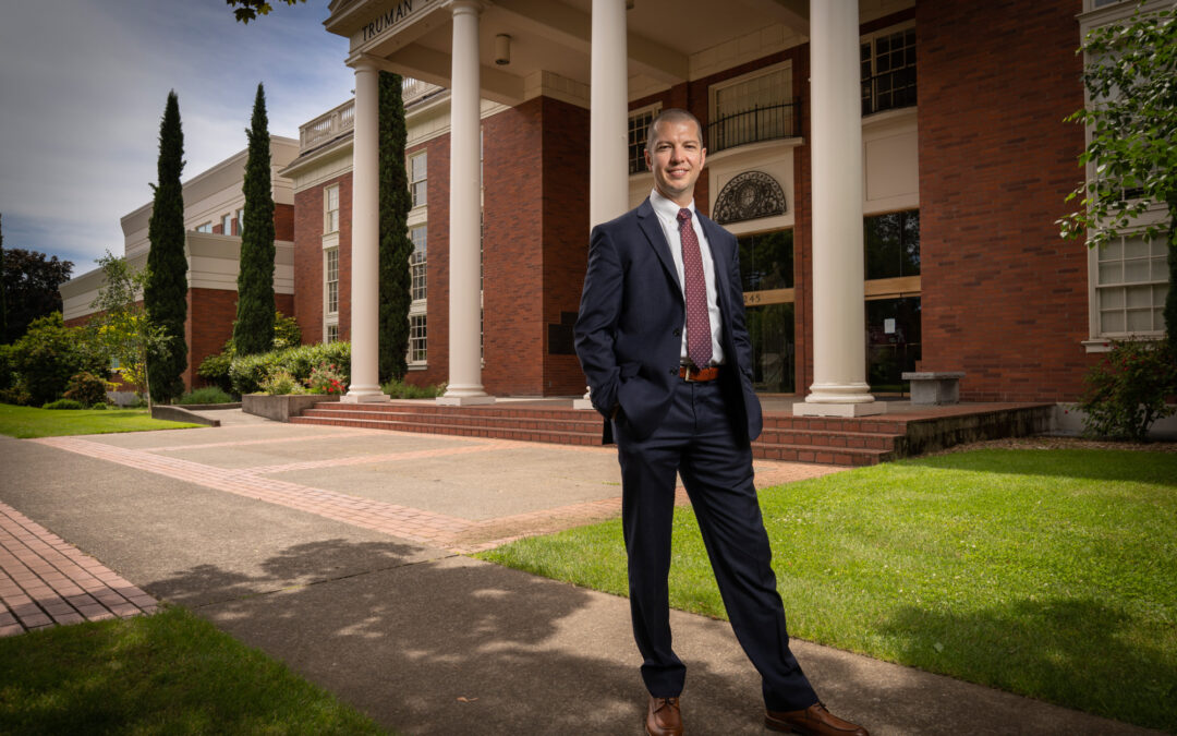 professionally dressed man standing in front of academic building