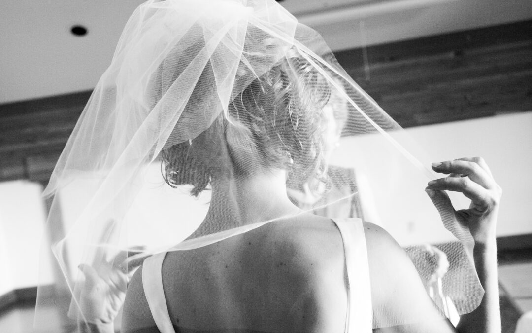black and white photo of bride trying on veil