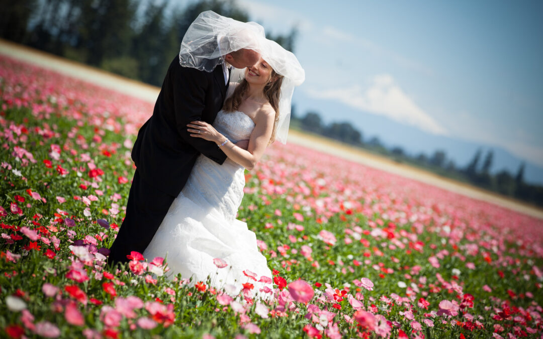bride and groom kiss in a field of flowers with mountain in background