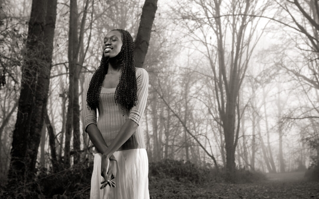 young black woman in misty forest with hands folded