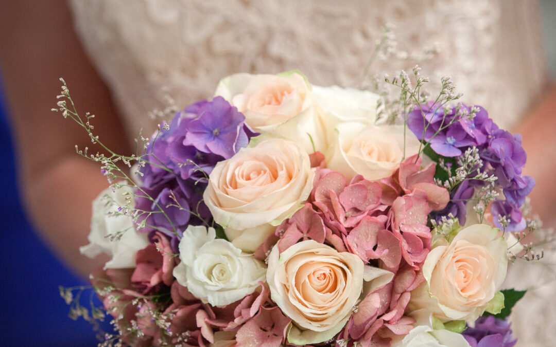 bride holding bunch of white and pink roses