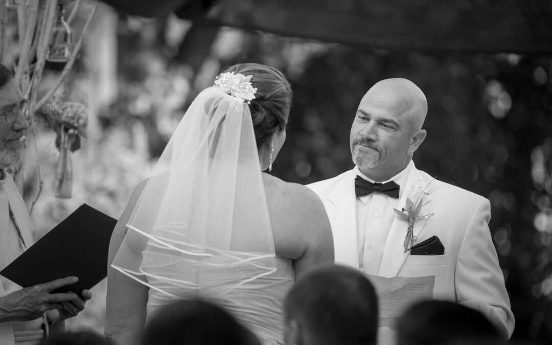 sincere middle aged man in white tuxedo speaks his wedding vows to his bride