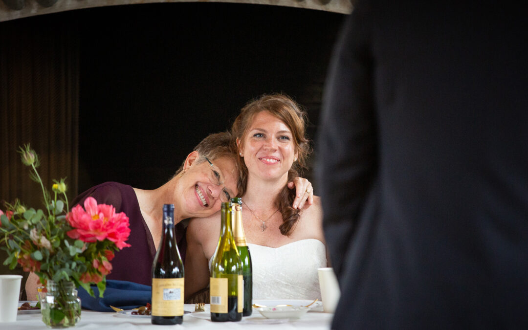 mother cuddles with bride at wedding