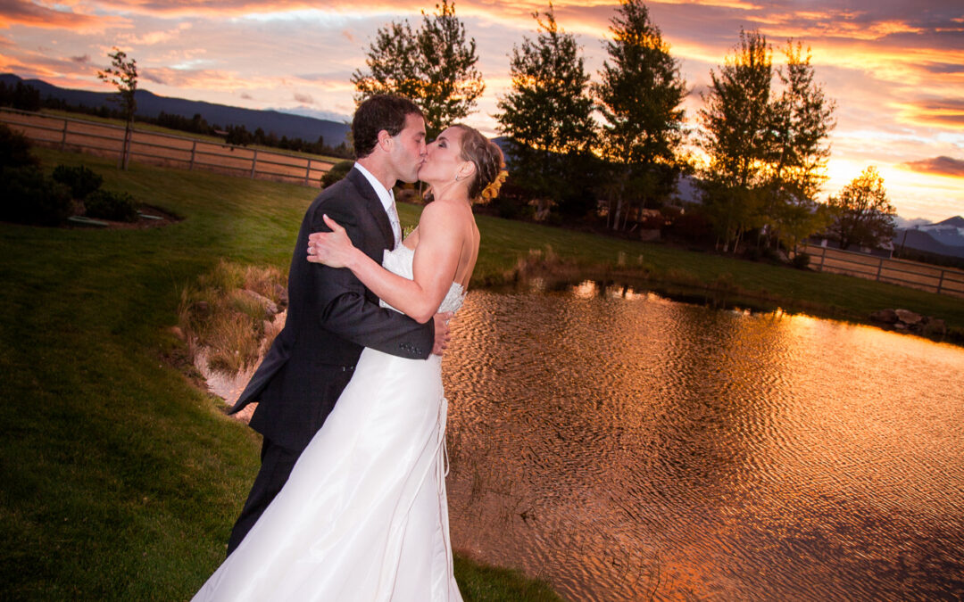 bride and groom kiss in front of dramatic sunset