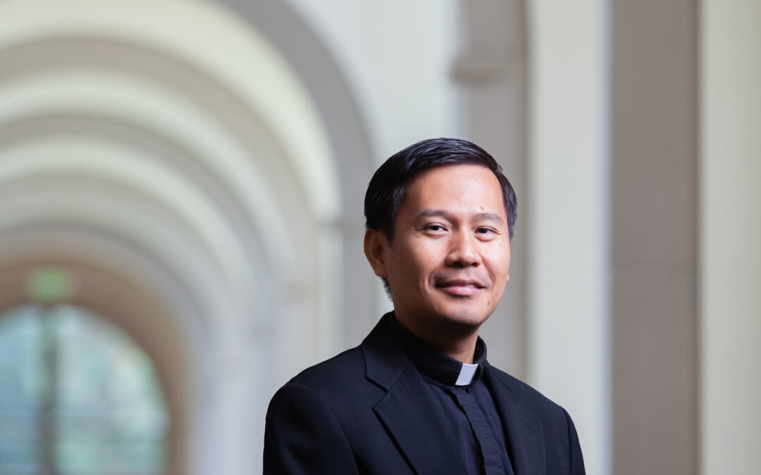 asian man in priest clothing framed by arched hallway