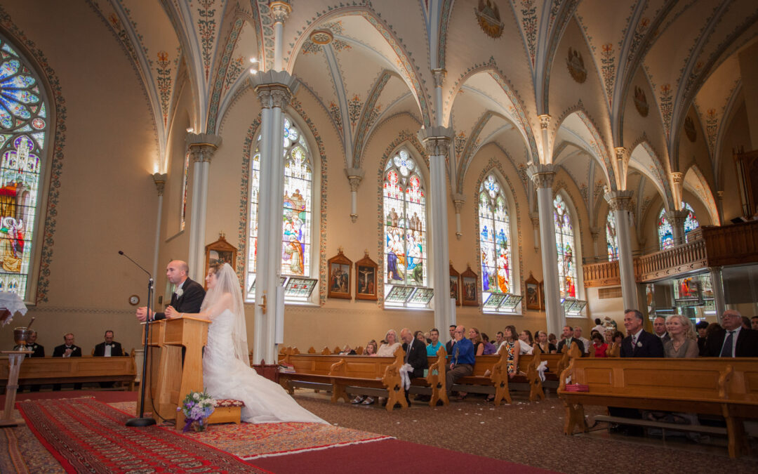 wedding ceremony in catholic church with stained glass windows