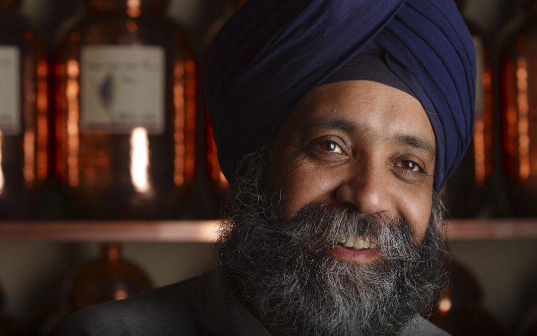 friendly man in turban with copper tea cans in background