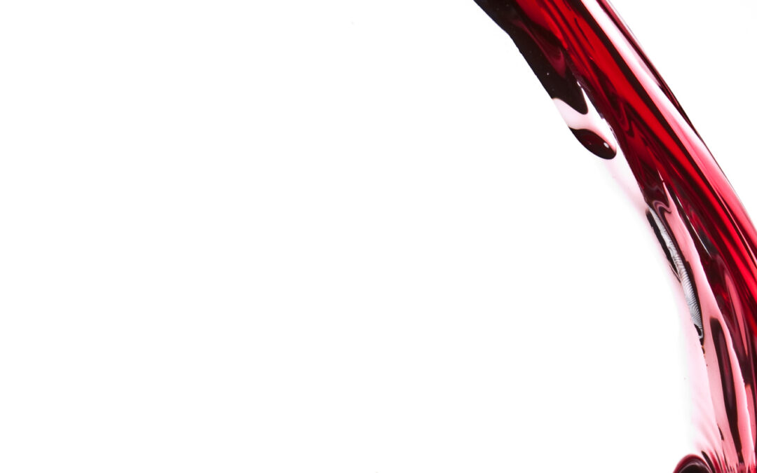 red wine pouring into glass on white background