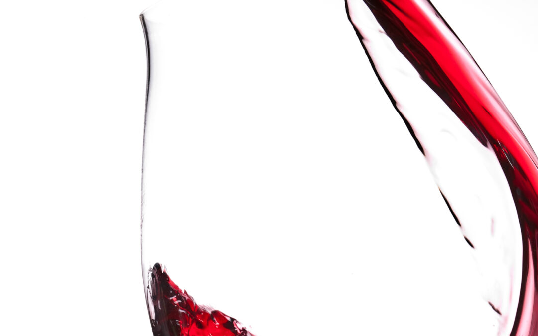 red wine pouring into glass on white background