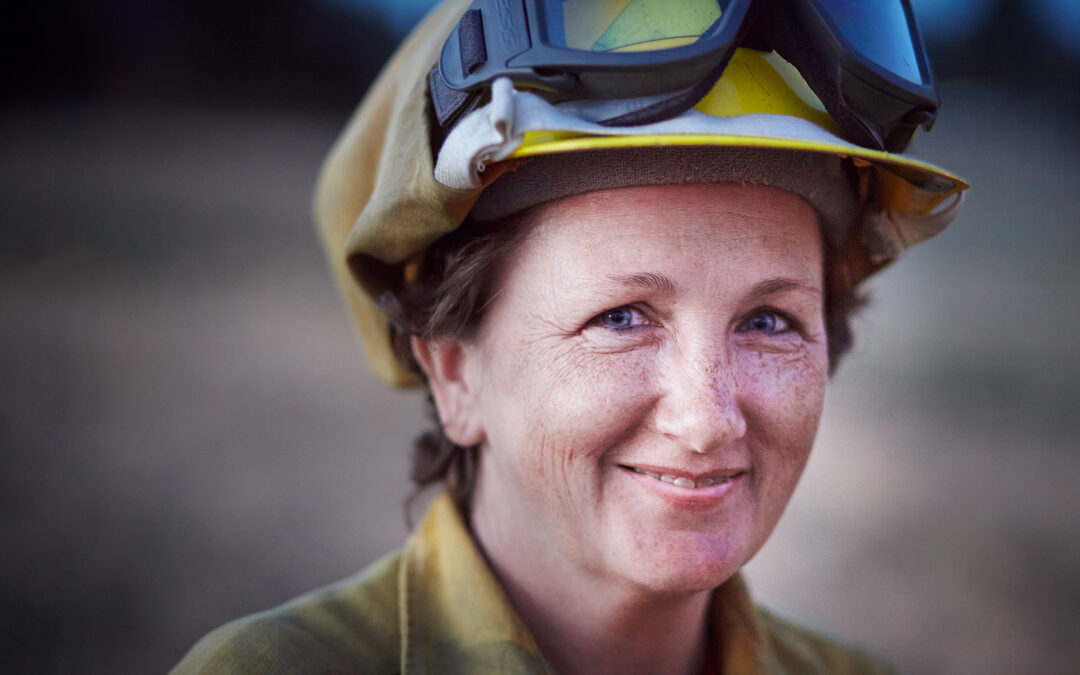 kind looking woman in firefighting gear smiling at camera outdoors