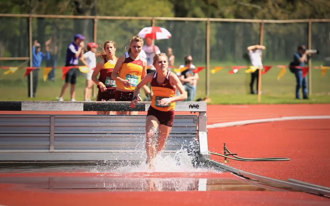 woman at track meet splashes after leaping over hurdle
