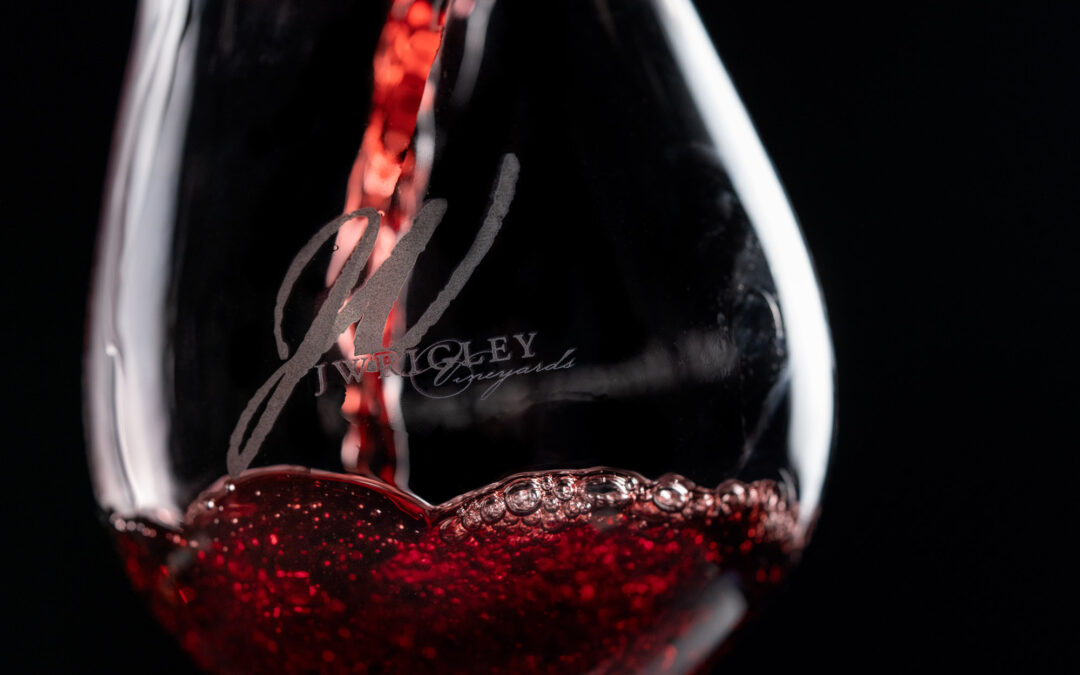 close up of wine glass with red wine being poured