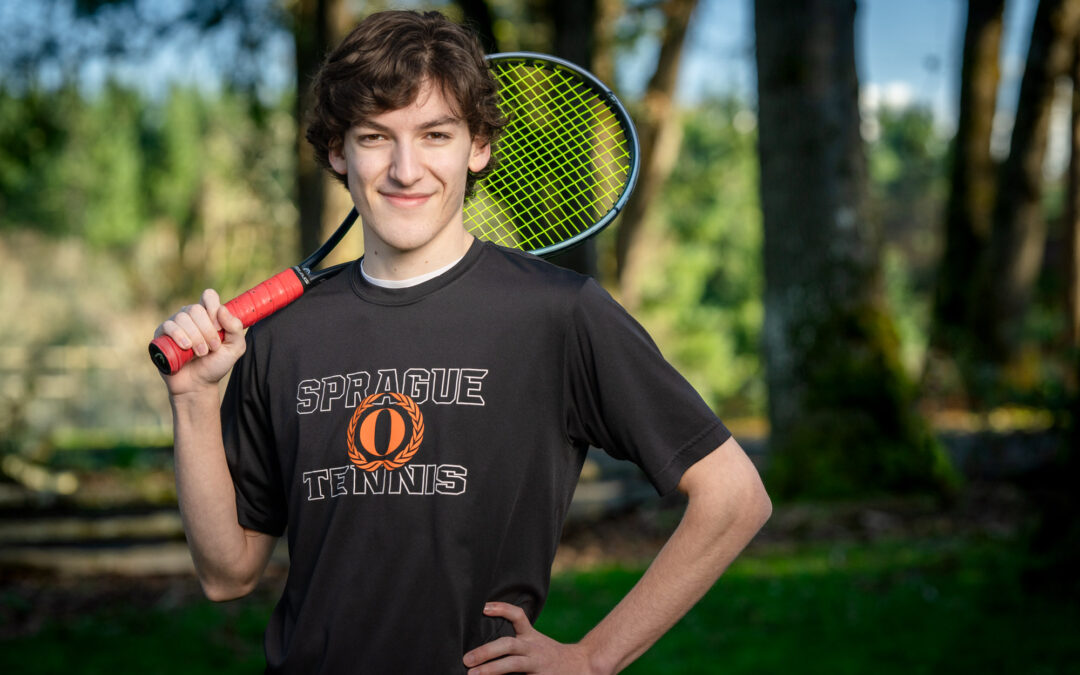 portrait of a smiling young man holding a tennis racket